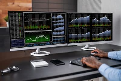 Trading desk with dual monitors showing candlestick charts for SPX and SPY options strategies